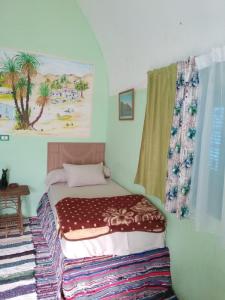 a small bedroom with a bed with a window at Aswan Nubian House in Aswan
