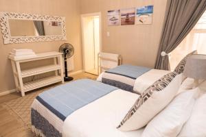 a bedroom with two beds and a mirror at Harbour View Selfcatering in Mossel Bay