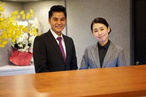 un hombre y una mujer de pie junto a una mesa en Beppu Daiiti Hotel en Beppu