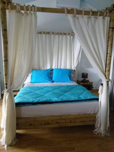 a bedroom with a bed with blue sheets and a canopy at Villa Hélèna B&B in Sainte-Marie