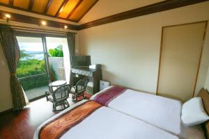 a bedroom with a bed and a balcony with a view at Ocean Hills Kouri in Nakijin