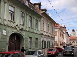 un bâtiment vert avec des voitures garées dans une rue dans l'établissement Poet Pastior Residence, à Sibiu