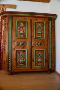 a wooden cabinet with paintings on it in a room at Landhaus Christina Alpbach in Alpbach +8 photos
