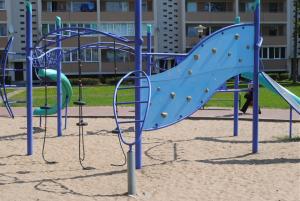 a playground with a blue slide in the sand at Park Apartment in Ventspils