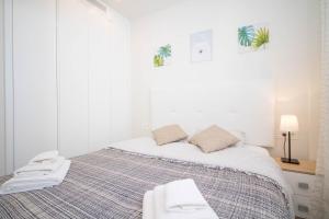 een witte slaapkamer met een bed met handdoeken erop bij El Mirador De Villamartin - La Zenia & Golf in Playas de Orihuela