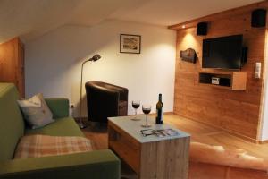 a living room with a couch and two glasses of wine at Landhaus Alpenhof in Fischen