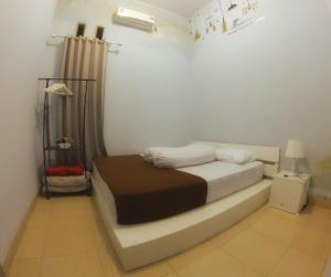 ein Schlafzimmer mit einem Bett in einem weißen Zimmer in der Unterkunft Rumah Ayin Homestay Near Airport in Palembang