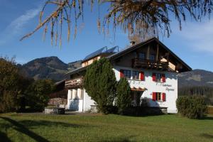 a house in the mountains with a tree at Landhaus Alpenhof in Fischen