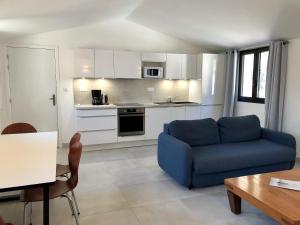 a living room with a blue couch and a kitchen at Les Appartements du Port in Bonifacio