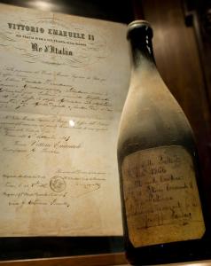 una bottiglia di vino seduta accanto a un documento di Rocche Costamagna Art Suites a La Morra