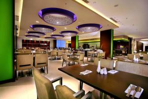 a restaurant with tables and chairs and purple lights at ASTON Purwokerto Hotel & Conference Center in Purwokerto