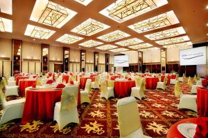 普禾加多的住宿－ASTON Purwokerto Hotel & Conference Center，一个带红色桌子和白色椅子的大型宴会厅