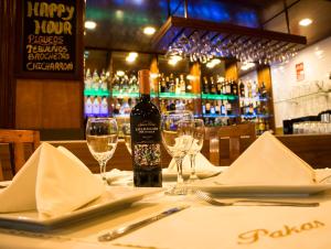 El Puerto Hotel في باكاسمايو: طاولة عليها زجاجة من النبيذ وكؤوس