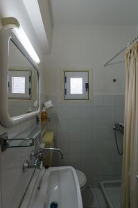 uma casa de banho branca com um lavatório e um espelho em Leonidio Rocks em Leonidion