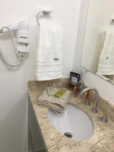 a bathroom with a sink and a mirror and towels at Apartamento novíssimo em Granja Viana in Cotia