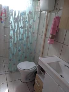 a bathroom with a toilet and a shower curtain at Casa de aluguel Gregório in Imbituba