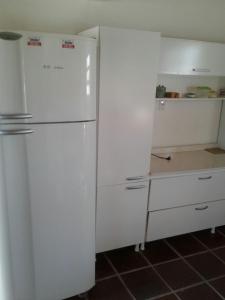 een keuken met een witte koelkast en witte kasten bij Casa Fávero Bairro Arco iris in Capão da Canoa
