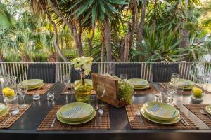 a table set with plates and glasses and a vase with flowers at Villa Sitges Tupinetti Beach at 1 min walk Amaizing Garden and View Center Sitges 5 minutes walk in Sitges