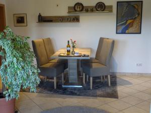 stół z 4 krzesłami i butelkę wina w obiekcie Ferienwohnung Am Waldrand w mieście Bad Breisig