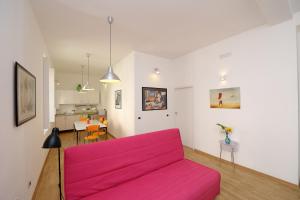 een woonkamer met een roze bank en een keuken bij Amalfi Holiday House Rooms & Apartments in Amalfi