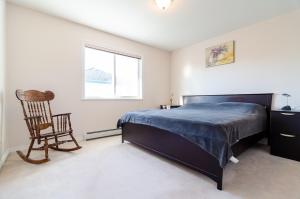 a bedroom with a bed and a chair and a window at 3 Private, spacious, bright rooms in a Gorgeous house in New Westminster