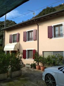 a house with purple shutters and a car parked in front at vololiberoapartments in Borso del Grappa