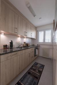 una cocina con armarios de madera y una alfombra en el suelo en Muhusin Apartments en Aarau