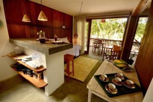 a kitchen with a counter and a table with dishes at Boa Village- Bungalow com Piscina Natural- Praia de Algodões in Marau