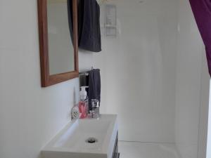 Sunset Accommodation في ويستبورت: حمام مع حوض أبيض ومرآة