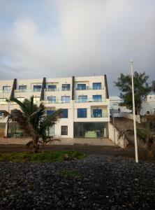 a white building with a palm tree in front of it at APARTAMENTO PTO LAJAS VISTAS AL MAR in Puerto de las Lajas