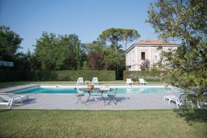 einen Pool mit einem Tisch und Stühlen neben einem Haus in der Unterkunft Borgo Sorbatti in Loro Piceno