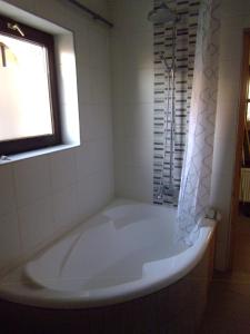 a white tub in a bathroom with a window at Aulich Apartman in Miskolc