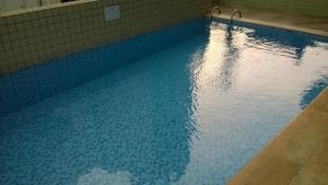 a blue swimming pool with a reflection in the water at APARTAMENTO MAX 7 in Praia Grande