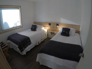 a hotel room with two beds and a window at Cabañas El Engaño in Chile Chico