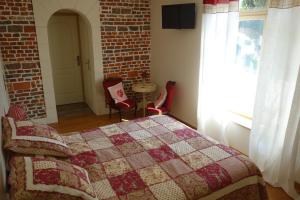 a bedroom with a bed and a brick wall at La Ferme De Tigny in Tigny-Noyelle