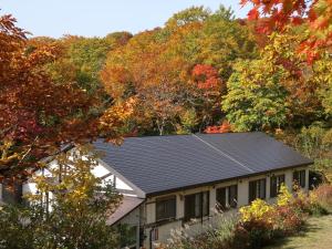 una casa con techo negro frente a los árboles en Yachi Onsen, en Towada