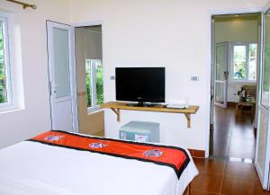 1 dormitorio con 1 cama y TV de pantalla plana en CucPhuong Resort, en Ninh Binh