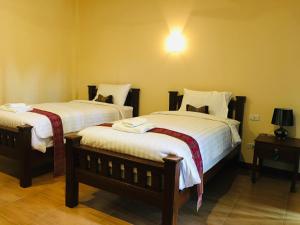 una camera con due letti con lenzuola bianche di Khao Lak Golden Coconut Resort a Khao Lak