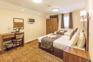 a hotel room with a bed and a desk at Prince Regent Hotel Excel London in London