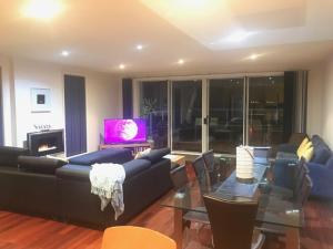 a living room with a couch and a table and a television at Cowes Beachfront Retreat in Cowes