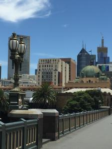 a street light with a city in the background at Flinders Street 238, CLEMENTS HOUSE at Federation Square, Melbourne, Australia in Melbourne