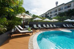 a swimming pool with chairs and umbrellas next to a hotel at Krabi Heritage Hotel in Ao Nang Beach