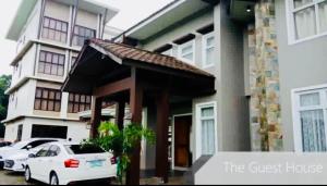 The Guest House Laoag في لواوْغ: سيارة بيضاء متوقفة أمام بيت ضيافة