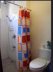 a bathroom with a toilet and a shower curtain at The Guest House Laoag in Laoag