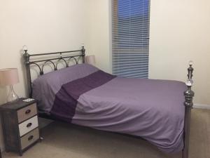 a bedroom with a bed with purple sheets and a nightstand at Flat 2 in Street