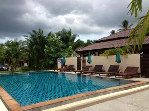 a swimming pool at a resort with chairs and umbrellas at Palm Sweet Resort in Chumphon