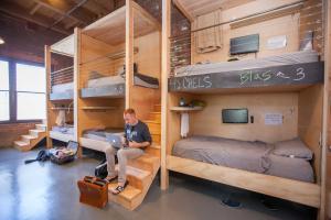 ロサンゼルスにあるポッドシェア DTLAの二段ベッドが備わる部屋に座る男性