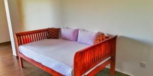 a wooden bed with pillows on it in a room at Divine View Homestay in Ella