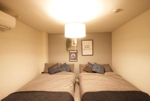a bedroom with two beds and a light fixture at Guest House Re-worth Joshin1 2F in Nagoya