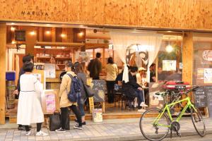 Guest House MARUYA في أتامي: مجموعة من الناس تقف خارج متجر